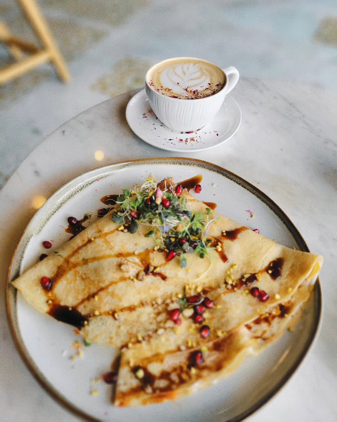 Breakfast crepe with latte served on a marble table