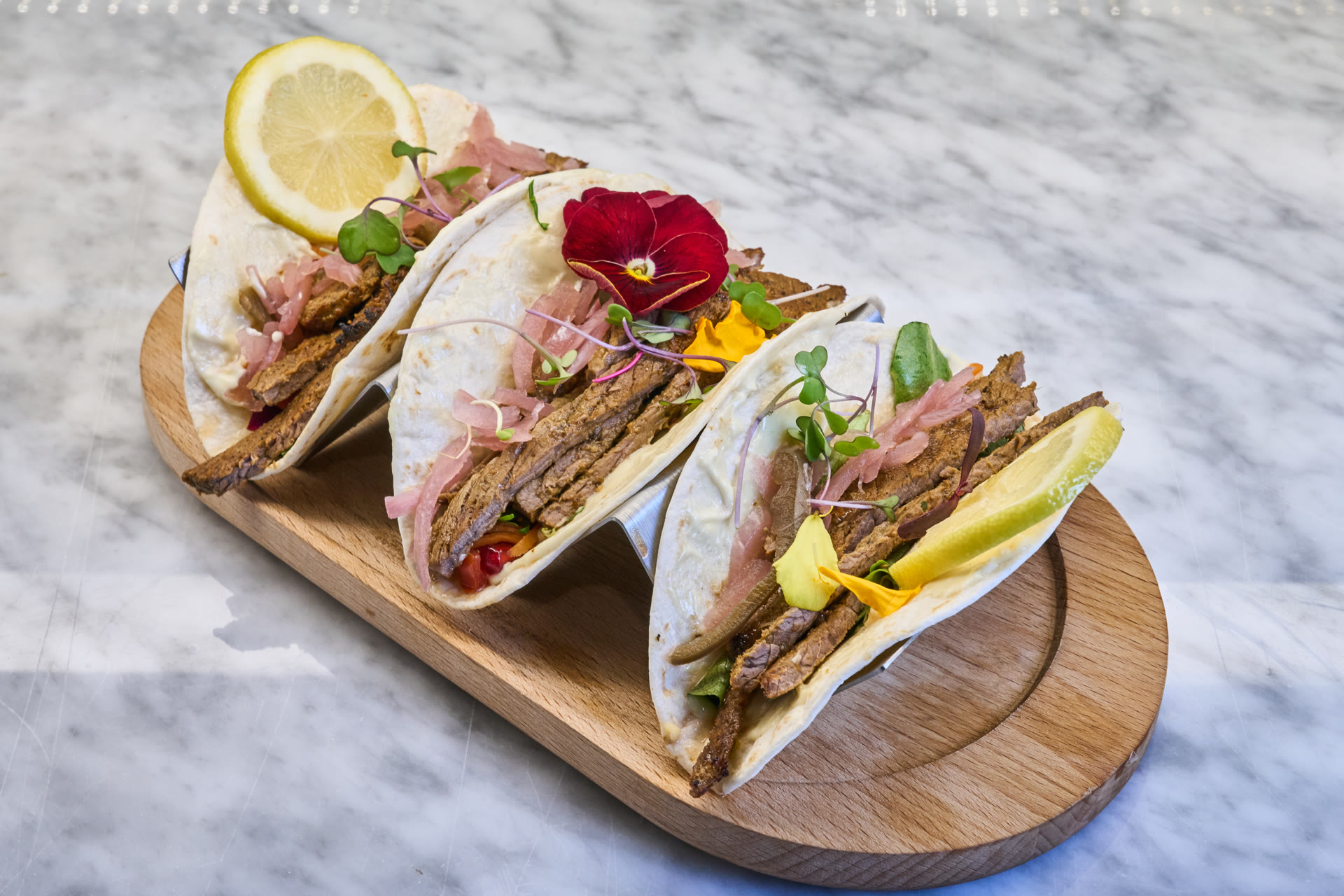 Moroccan steak tacos served with lemon, herbs and edible flowers