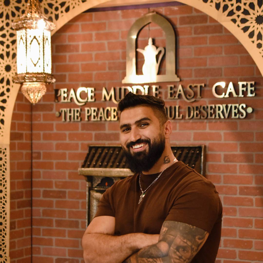 Peace Middle East founder in front of the cafe slogan wall