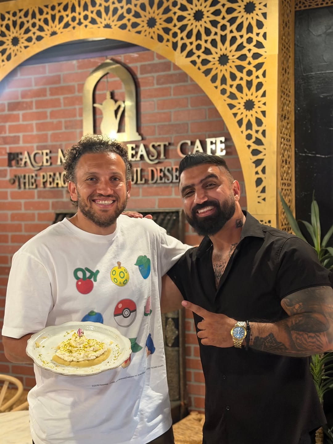 Peace Middle East Cafe founder smiling with a guest holding a dessert plate
